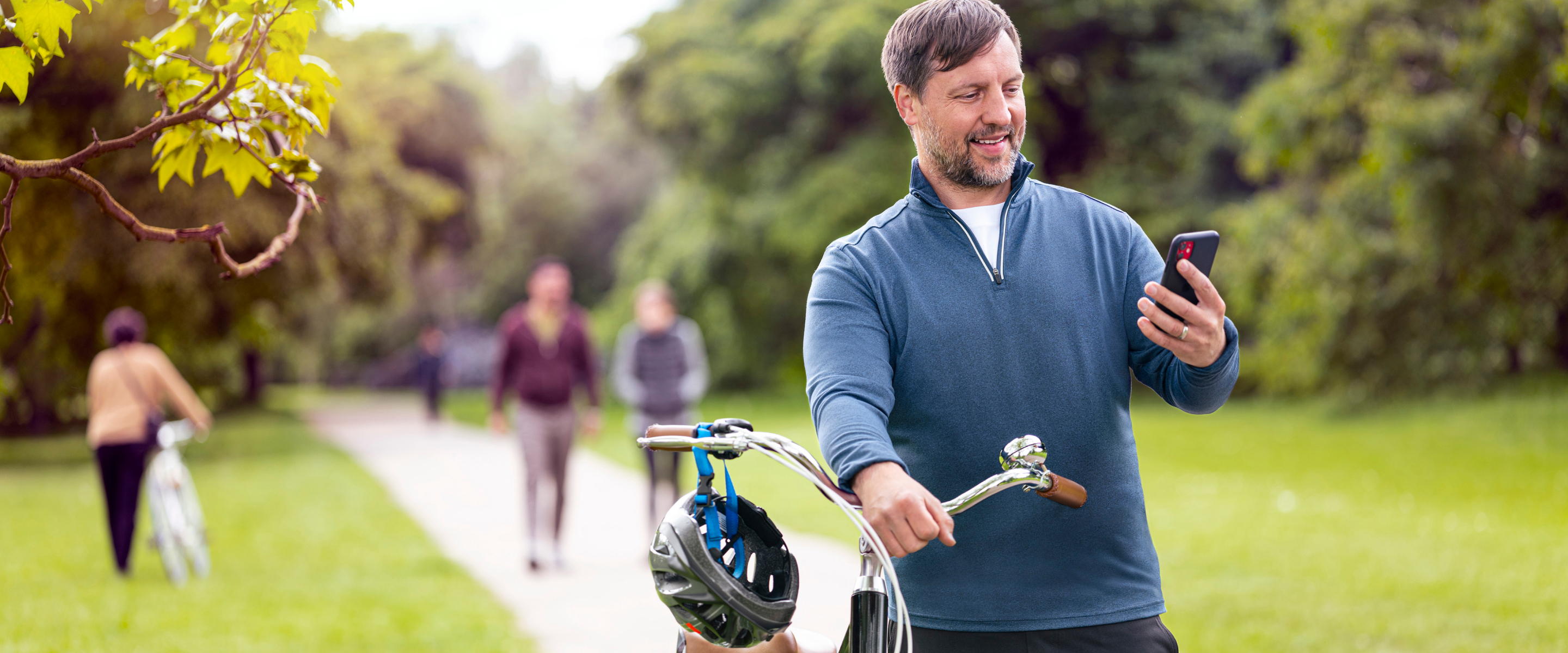 A smiling man in park, standing with bike and holding smartphone, using the TempoSmart App